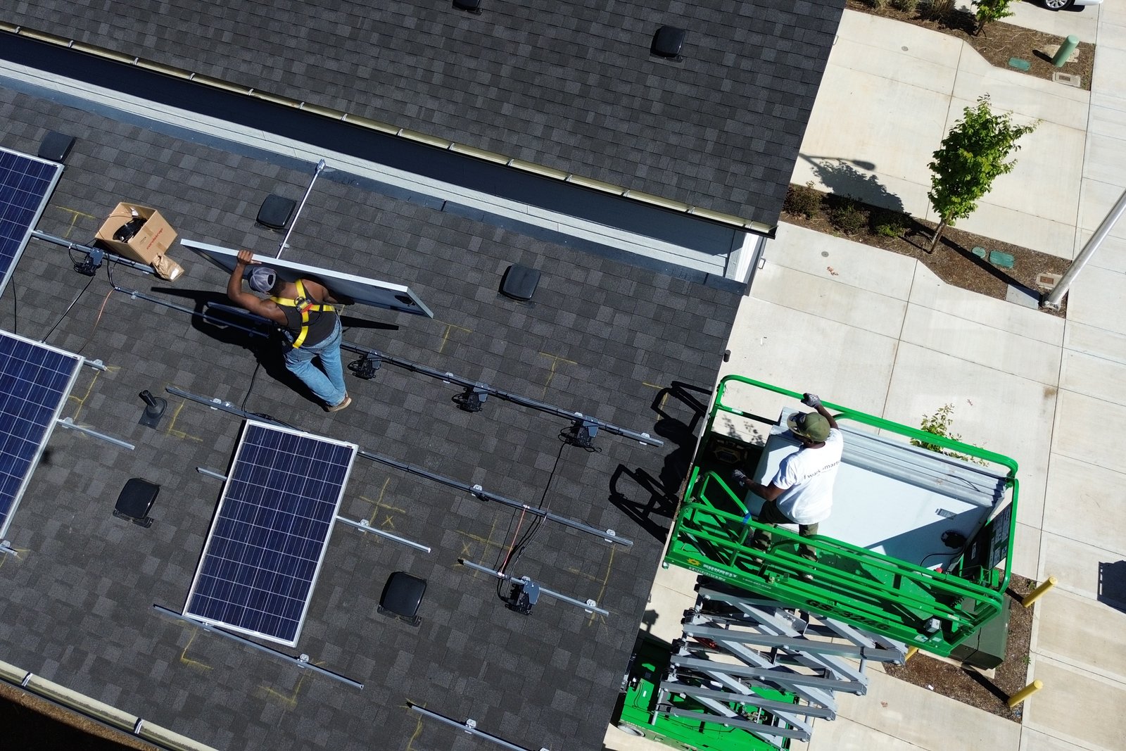 Installers moving panels up to the roof from a lift